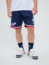 Short deportivo Umbro del Club Nacional de Football, modelo Match para hombre. Diseño en color azul marino con tejido de malla, detalles en blanco y rojo en los laterales y el escudo del club bordado.