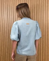 Camisa de algodón a rayas color beige y blanco, con escote en V, cuello mao y mangas cortas abullonadas. Cuenta con cierre frontal de botones oscuros.
