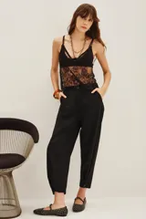 Pantalon de vestir negro de corte sastrero, con tiro medio, bolsillos laterales y botamanga con detalle de botón.