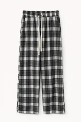 Pantalón de pijama de corte recto y holgado, confeccionado en tela de franela con estampado de cuadros en tonos marrones, negros y blancos. Cuenta con cintura elástica y cordón de ajuste frontal.