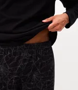 Pijama largo de hombre confeccionado en algodón, compuesto por una remera negra de manga larga con cuello redondo y estampa localizada de Spider-Man en el pecho, y un pantalón con estampado integral de telarañas y cintura elástica.