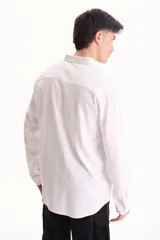 Camisa de lino de manga larga, color beige, con cuello clásico y cierre frontal de botones.