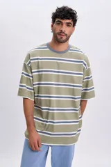 Remera de manga corta con diseño de rayas horizontales en tonos verde, blanco y azul, de corte oversize y cuello redondo en color gris.