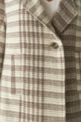 Saco corto de tela a cuadros color beige y marrón, con cuello solapa, manga larga y cierre frontal con un botón. Tiene un bolsillo de parche en el frente.
