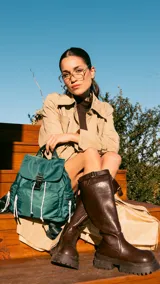 Mochila verde de nylon con tapa y broche metálico, apertura superior con cierre marinero, bolsillos internos, bolsillo con cierre metálico al frente y laterales, asas rígidas de mano y correas regulables para colgar en la espalda.