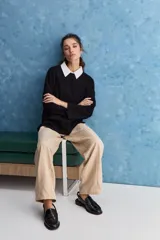 Sweater blanco de punto con diseño holgado, cuello redondo, mangas largas acampanadas y detalles de textura horizontal en el tejido.