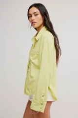Blusa de lino color blanco crudo, de corte relajado, con cuello clásico, cierre frontal de botones, bolsillo en el pecho y mangas largas con presillas para arremangar.