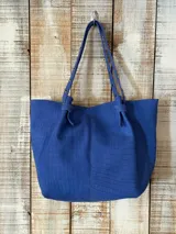Bolso shopper grande color azul con textura efecto cocodrilo, asas dobles de hombro decoradas con tachas metálicas y costura central vertical.