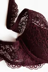 Soutien push-up con aros y copas con relleno, confeccionado en encaje color vino tinto. Presenta bordes festoneados en las copas y en la base, y tirantes anchos con borde festoneado.