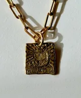 Collar de plata con cadena de eslabones alargados y dije de medalla rectangular con textura rústica, grabado en relieve con forma de estrella y una piedra brillante incrustada en el centro.