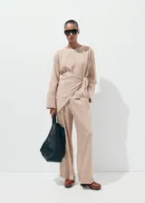 Pantalón de tiro medio color beige con diseño a rayas sutiles, de corte recto y holgado, confeccionado en mezcla de lyocell, viscosa y poliamida.