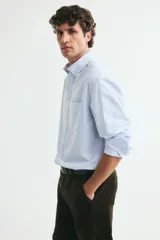 Camisa de algodón H&M Oxford con estampado de rayas verticales celestes y blancas, cuello americano, bolsillo en el pecho y manga larga.