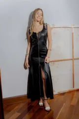 Vestido largo de cuero ovino negro con cierre frontal completo, escote redondo y detalles de hebillas metálicas en color platino en los hombros.