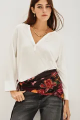 Remera de manga larga en color blanco, confeccionada en una mezcla de lino y viscosa. Presenta un escote en V con detalle de solapa y puños rectos.