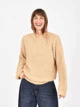 Buzo de tejido de punto grueso en color beige, con cuello redondo y mangas largas de corte holgado.