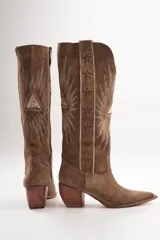 Botas texanas de cuero color marrón con bordados blancos en forma de estrellas y rayos.