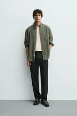Pantalón de corte recto confeccionado en tejido elástico, con cintura elástica, pliegues frontales, bolsillos laterales y bolsillos traseros de vivo con botón.