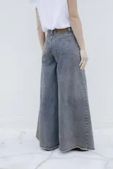 Pantalón de jean estilo palazzo, de tiro medio y lavado deslavado, con diseño amplio en las piernas y costuras frontales destacadas.