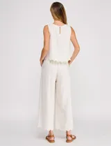 Pantalón palazzo de tiro alto color beige, confeccionado en mezcla de lino y viscosa, con silueta suelta y fluida, cintura elastizada, bolsillos delanteros aplicados y ruedo festoneado de corte tobillero.