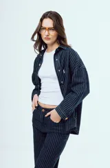 Camisa de denim azul oscuro con diseño de rayas diplomáticas blancas, de corte oversize, con mangas largas y bolsillos frontales con solapa.