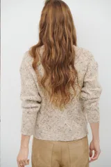 Buzo de punto con cuello redondo, manga larga y textura jaspeada en tonos beige y crema.