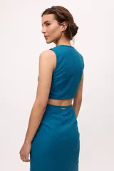 Vestido azul con corte midi, sin mangas y escote en V. Presenta un corte a la altura de la cintura con abertura circular.