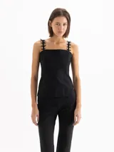 Top de lycra doble color negro, de calce ajustado y largo hasta la cadera. Presenta recortes de entalle en el delantero y la espalda, escote recto y breteles con detalle de cintas formando moños.