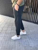 Pantalón jeans de corte slouchy, color negro gastado, suelto en la parte superior y ligeramente ajustado hacia los tobillos.