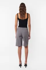 Short tipo bermuda recta de largo jort, color gris, tiro medio. Tiene cordón con punteras y tancas metálicas, cierre y botón. Incluye pasacintos, bolsillos laterales delanteros y dos bolsillos traseros. Detalle de llavero TW.