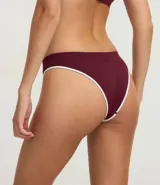 Bombacha tipo bikini de corte clásico, confeccionada en tejido de poliamida texturizado con tecnología seamless. Presenta un diseño liso en color bordó con bordes en contraste color blanco y detalle de logo bordado en el frente.