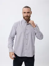 Camisa de corte clásico confeccionada en tejido Oxford de algodón, con cuello abotonado, manga larga y bolsillo frontal en el pecho.