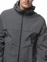 Campera rompevientos de nylon color gris, con capucha ajustable, cierre frontal completo, bolsillos laterales con cierre, puños elásticos y ruedo ajustable.