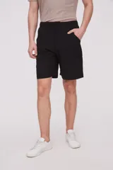 Bermuda de corte recto y diseño minimalista, confeccionada en tejido técnico de poliéster. Presenta cintura elástica con cierre de botón frontal, bolsillos laterales y un bolsillo pequeño adicional en el lateral izquierdo.