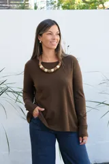 Sweater de punto color chocolate, con cuello redondo, manga larga y puños acanalados. Presenta un corte holgado con ruedo asimétrico.