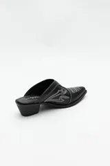 Zueco estilo texano en color plateado, con punta fina, bordados decorativos en la capellada y taco cuadrado de 5 cm.