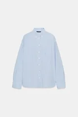 Camisa de manga larga con patrón de rayas verticales en tonos celeste y blanco, cuello con solapa abotonada y un bolsillo aplicado en el pecho. Cierre frontal con botones blancos.