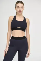 Top deportivo negro con escote redondo, espalda deportiva y abertura geométrica en el centro del pecho.