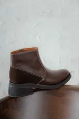 Bota corta de cuero marrón con panel trasero de gamuza en tono más oscuro, suela de goma negra y taco cuadrado bajo.