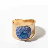 Brazalete rígido dorado con aplicación de piedras azules.