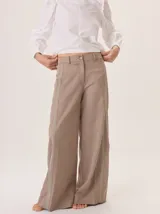 Pantalón de pierna ancha color beige, con pespuntes a contratono y una tira vertical contrastante en el lateral que estiliza la figura.