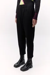 Pantalón negro estilo chino con elástico en la cintura y cierre metálico en la pierna.