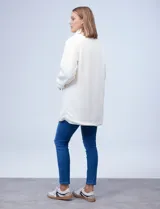 Cárdigan largo reversible color blanco. Un lado es de sherpa y el otro capitoneado. Tiene bolsillos delanteros.