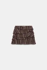 Falda pantalón corta con diseño de volantes superpuestos, confeccionada en tejido estampado a rayas con hilos metalizados. Cuenta con forro interior y cierre lateral con cremallera oculta.