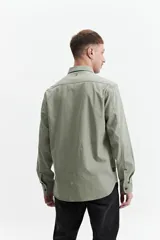 Camisa manga larga color verde oliva, corte slim fit, con cartera abotonada, dos bolsillos frontales con botón y confeccionada en 100% algodón.