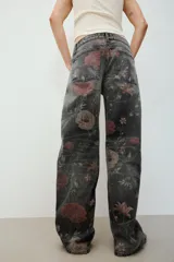 Jeans de tiro bajo y corte holgado de denim negro, con estampado floral en tonos rosados y verdes. Cuenta con diseño de cinco bolsillos y trabillas para cinturón.