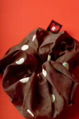 Colitapelo scrunchie de tela marrón con lunares amarillos.