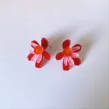 Aros tipo botón con forma de flor de pétalos turquesa y centro rosa y naranja.
