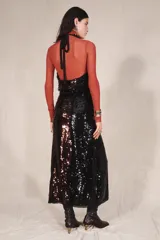 Vestido largo de lentejuelas con cuello halter, espalda descubierta y lazos para atar al cuello. Cuenta con un cinturón de lazo en contraste y diseño bicolor que combina tonos tostados y negros.
