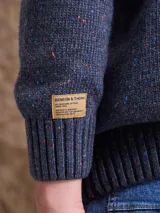 Cardigan de punto con textura en relieve, cuello smoking y cierre frontal completo. Presenta un diseño jaspeado con pequeños puntos de color y bolsillos laterales.