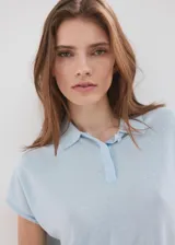 Chaleco de tejido de punto fino color celeste con sutiles lentejuelas, cuello polo y cierre delantero parcial con botones.